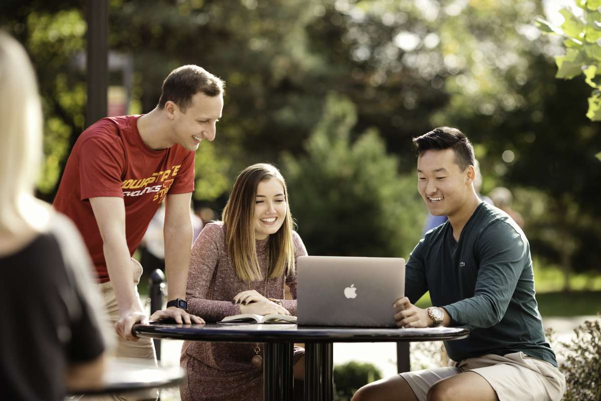 Three students sitting around a computer smiling
